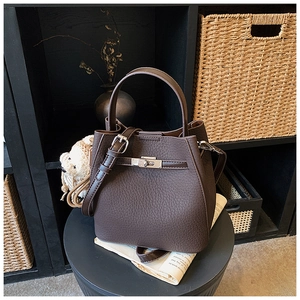 Detail of dark brown litchi pattern leather bucket bag with a plush bear pendant
