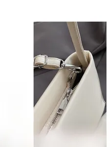 Close-up of sleek silver hardware and zipper details on a cream leather shoulder bag