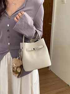 Minimalist beige pebble leather bucket handbag with silver buckle and plush bear charm