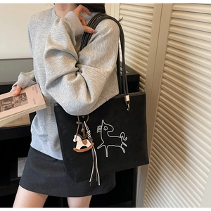 Detail of black tote bag featuring white horse embroidery and colorful horse charm
