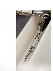 Macro shot of high-quality silver metal zipper and cream leather texture on handbags