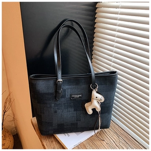 Detail of dark blue denim tote bag featuring leather logo tag and white horse charm