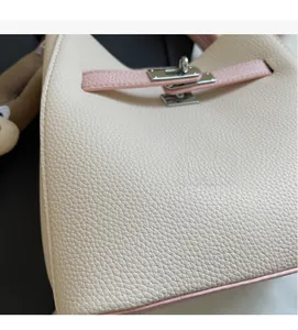 Close-up of contrast color bucket bag showing off-white lychee grain leather and metal lock