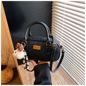 Détail du sac à main noir grainé avec plaque dorée et pendentif ours en peluche doux
