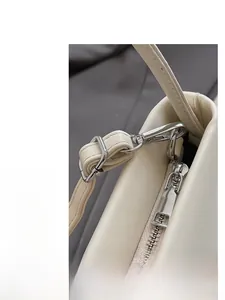 Detail shot of premium silver hardware and leather texture on the cream baguette bag