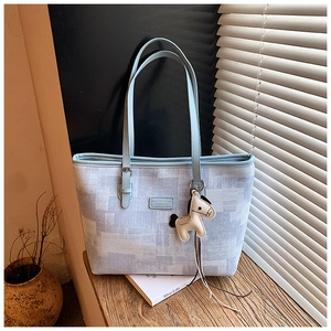 Detail of contrast color tote bag with beige horse charm in French style lighting