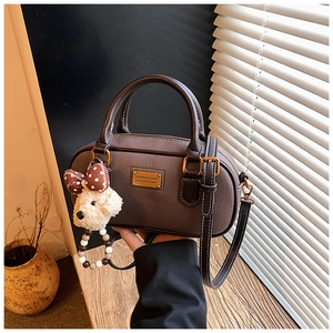Détail du sac Boston en cuir café avec surpiqûres blanches et charme chien en peluche