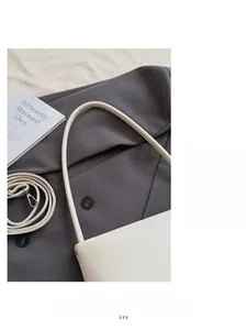 Detail view of cream white faux leather shoulder bag with wide integrated strap and smooth finish