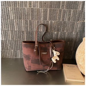Close-up of contrast color tote bag with leather straps and a horse charm detail