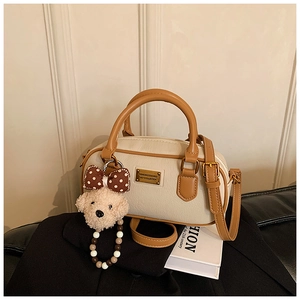 Détail du sac à main Boston en cuir crème, garnitures dorées et pendentif d'ours en peluche