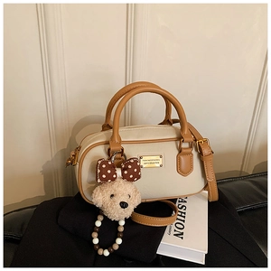 Détail du mini sac Boston blanc cassé avec poignées marron et breloque ours en peluche