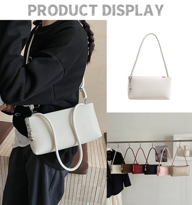 Detail view of stylish leather underarm bag featuring a silver artistic pendant