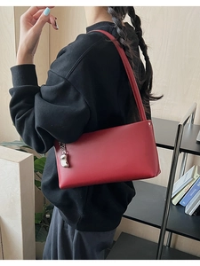 Detailed side view of deep red minimalist shoulder bag with silver bean pendant