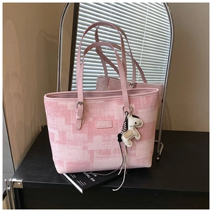 Detail of pink tote bag with pixel print, slim straps and a horse charm accessory