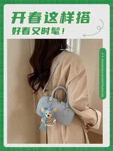 Gros plan du sac bowling bleu clair avec un ours en peluche sur une chemise beige