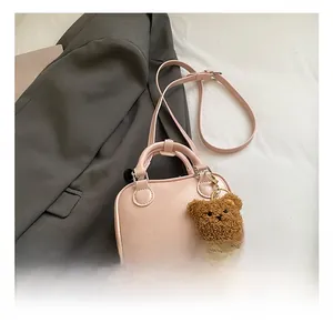 Detailed view of pink mini handbag with bear pendant on grey blazer background