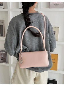Close-up of pink minimalist baguette bag with silver charm and slim shoulder strap