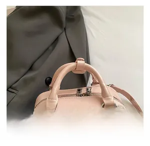 Detailed view of pink leather handbag with pleated texture and soft top handle