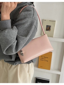Detail of light pink shoulder bag with a silver metal pendant worn with casual outfit