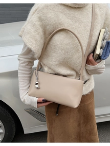 Beige faux leather shoulder bag with silver chain detail shown on a model's arm