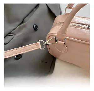 Detail shot of silver metal hooks and zipper on light pink textured leather bag