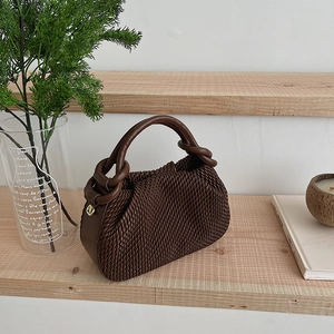 Top view of a dark brown bucket bag with woven texture on wooden stairs with plants