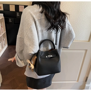 Detail of black lychee grain leather bucket bag with silver buckle and plush charm