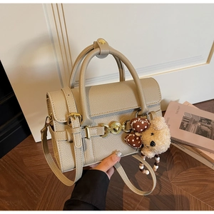 Detail of lychee pattern leather bag with golden heart buckle and plush bear charm