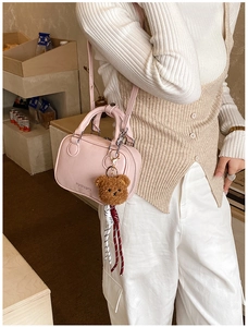 Detail of light pink mini bag with brown plush bear charm and woven rope decoration