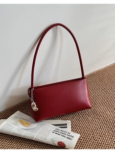 Close-up of dark red shoulder bag featuring smooth leather and silver bean charm
