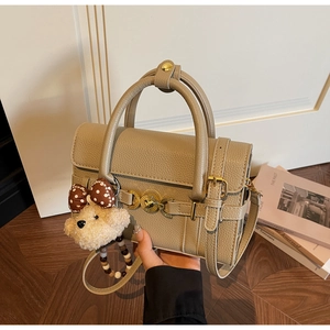 Detail of khaki textured leather handbag with gold heart lock and plush bear charm