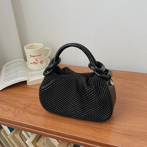 Close-up of a black pleated bucket bag showing detailed texture and metal ring buckle