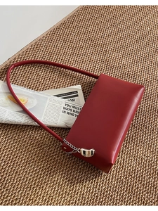 Detail of red faux leather handbag with silver chain and FASHION pendant on woven mat