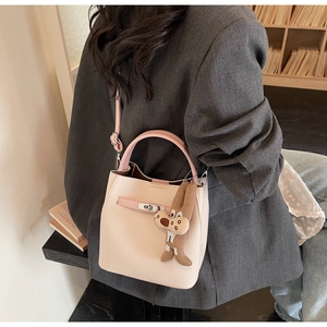 Detail of pink lychee leather bucket bag with squirrel pendant and metallic twist lock