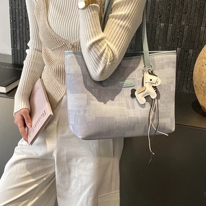 Detailed texture of blue checkered tote bag with a white horse charm and leather patch
