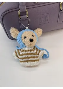 Close-up of a cute knitted bear charm with a striped sweater on a purple handbag