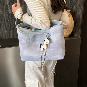 Detail of blue textured tote bag with leather straps and decorative horse charm