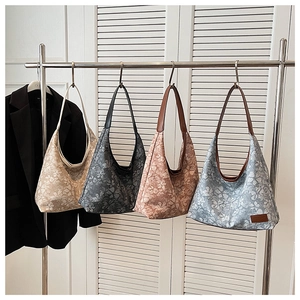 Macro detail of floral jacquard hobo bags in four colors hanging on a metal rack