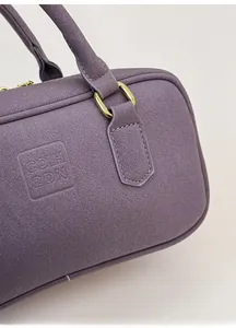 Detail of purple lychee grain leather bag with gold hardware and embossed COIH 2DN logo