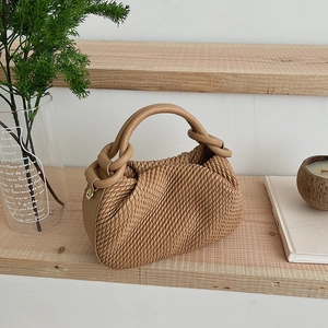 Detail of the woven texture and circular handle attachment on this camel bucket bag