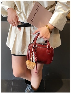 Fashionable burgundy leather mini handbag featuring a cute plush bear charm decoration