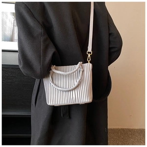 Detail of pleated texture and gold metal buckle on light gray crossbody bucket bag