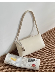 Detail of cream white faux leather shoulder bag with crescent silver chain charm