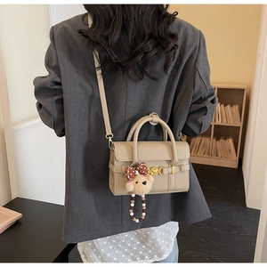 Close-up of beige lychee grain crossbody bag with vintage gold hardware and bear charm