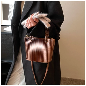 Detail of pleated texture on a brown hobo bag with round metal eyelets and leather handle