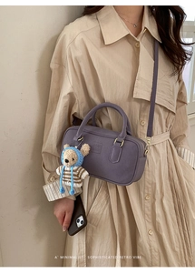 Detail of purple Boston bag with COIH RDN embossing and cute bear charm on beige trench coat