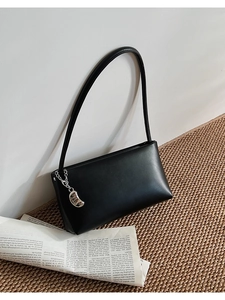 Detail shot of black minimalist PU leather shoulder bag with a silver bean chain charm