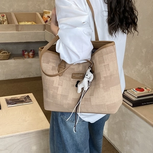 Detail of contrast stitch tote bag with leather trim and cute cartoon dog keychain