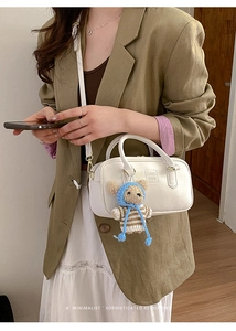 Close-up of white mini Boston bag with textured leather and a cute plush bear charm