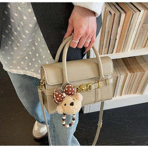 Detail of beige lychee grain leather bag with heart twist lock and plush bear charm